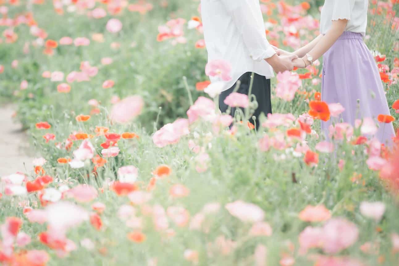 花畑で手を取り合うカップル
