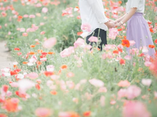 花畑で手をつなぐ男性と女性